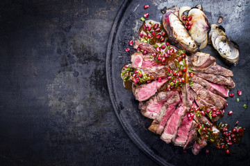 Barbecue dry aged caveman wagyu porterhouse steak with onion and pomegranate salsa as top view on a...