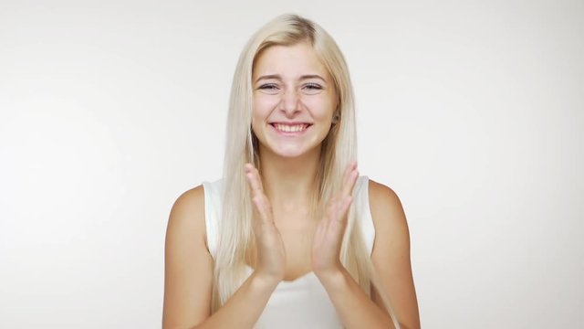 caucasian happy young woman with long blond hair expressing approval showing thumb up smiling clapping over white background. Concept of emotions
