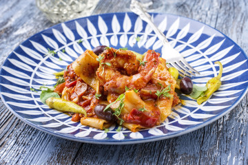 Italian tagliatelle con gamberi e calamari in salsa di pomodoro with olives and peperoni as close-up on a plate