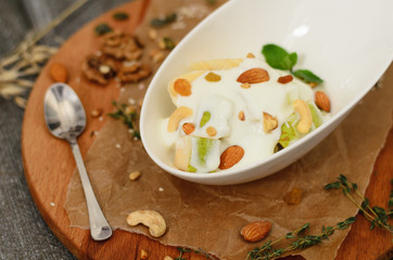 Fruit salad with yogurt and nuts in a bowl on desk on wooden background