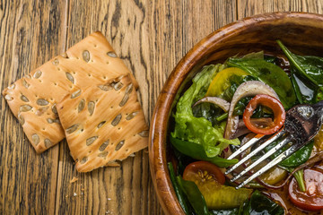Fitness salad in a wooden bowl on old wooden table. Fresh aromatic vegetables. The appearance of appetite. The view from the top. A place for Your inscriptions.