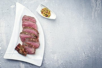 Barbecue dry aged Kobe chateaubriand steak with fruit relish as close-up on a white plate