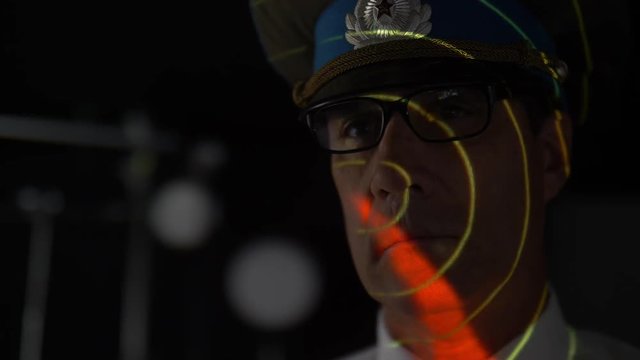 RUSSIAN COMMANDER LOOKS AT RADAR.  Version 1 of 2.  Radar screen light on his face.  Model release.