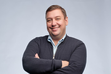 Half body portrait of confident middle aged man with folded arms looking at camera