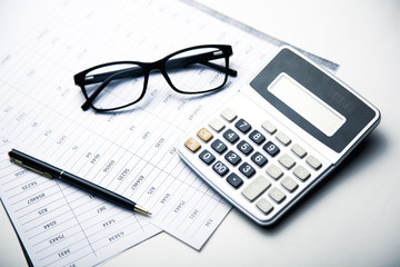 Naklejka na ściany i meble Glasses and calculator on paper table with finance report