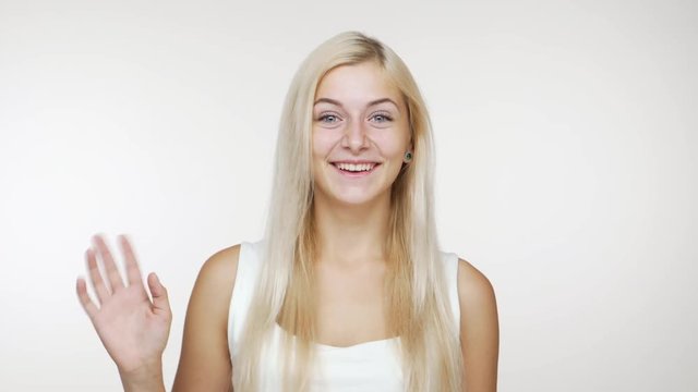 cheerful blondie woman laughing welcoming waving hand saying "hi" on camera over white background. Concept of emotions