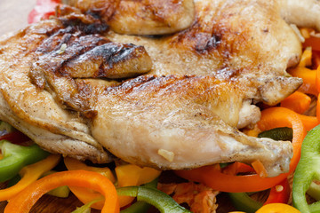 Fried crusted grilled chicken on a colorful background of vegetables