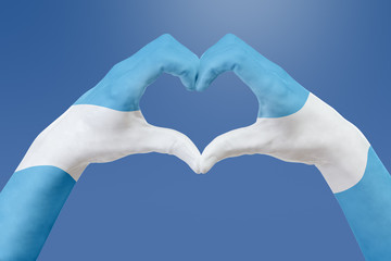 Fototapeta premium Ręce flaga Argentyny, kształt serca. Pojęcie symbolu kraju, na błękitnym niebie.