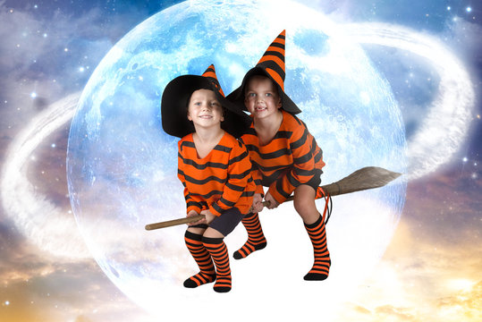 Halloween.Two of the boy wizard fly on broomstick across the sky.Beautiful children in Halloween costumes.