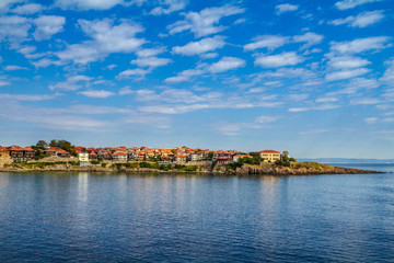 Fototapeta premium Coastal landscape - the rocky seashore with houses under the sky with clouds, town of Sozopol on the Black Sea coast in Bulgaria