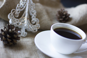 A cup of coffee and some chocolate with autumn leaf on the foreground.