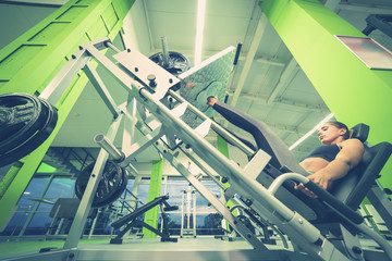 The sportswoman doing exercise for legs in the sport center