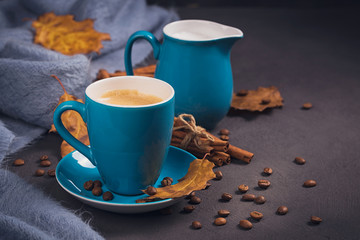 Blue cup of coffee with coffee beans and autumnal dry leaves
