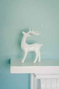 white ceramic reindeer on mantlepience against a blue wall