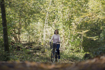 Obraz premium Woman riding bicycle in forest