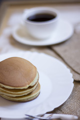 A perfect breakfast combo of jam, pancakes, and a hot cup of coffee.