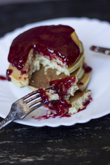 A perfect breakfast combo of jam, pancakes, and a hot cup of coffee.