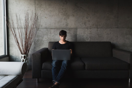 Man sitting on couch using laptop computer