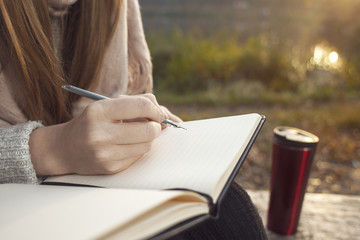Girl writes book in the autumn park