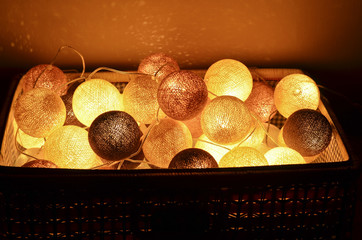 Christmas and New Year cotton light balls in a basket glowing in the dark. Creative decoration.
