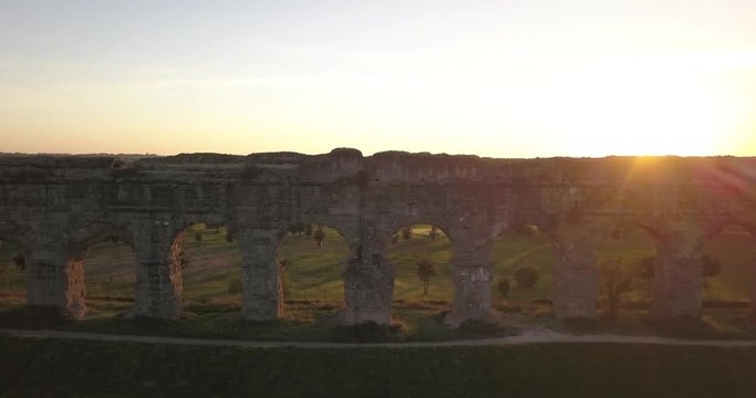 Video from above. Aerial view of the ancient Roman Aqueduct at sunset. Old ruins surrounded by a green public Park (Parco degli Acquedotti) Rome, Italy.