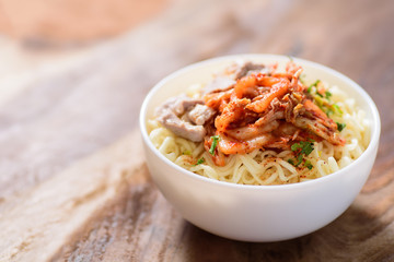 Korean food,instant noodle with kimchi cabbage in a bowl on wooden background