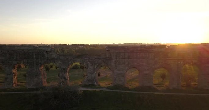 Video from above. Aerial view of the ancient Roman Aqueduct at sunset. Old ruins surrounded by a green public Park (Parco degli Acquedotti) Rome, Italy.