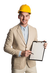 Handsome construction worker wearing a bright blazer holding a clipboard with a yellow safety helmet on his head. White background.