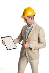Handsome construction worker wearing a bright blazer holding a clipboard with a yellow safety helmet on his head. White background.