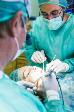 Two dentists with a woman patient during a implant intervention