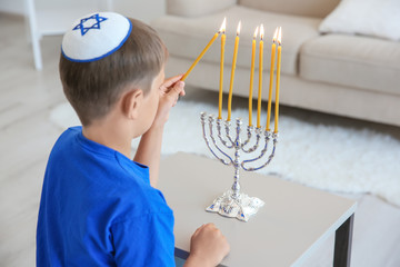 Jewish boy lightning menorah at home