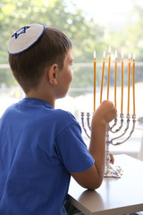 Jewish boy lightning menorah at home © Africa Studio