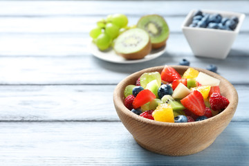 Bowl with delicious fruit salad on wooden background