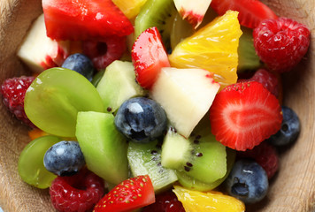 Delicious fruit salad in wooden bowl, closeup