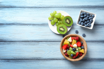 Bowl with delicious fruit salad on wooden background