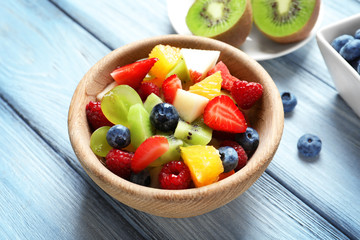 Fototapeta na wymiar Bowl with delicious fruit salad on wooden background