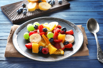 Plate with delicious fruit salad on table
