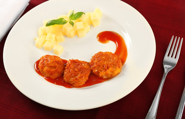 Plate with tasty sausage balls and garnish on table