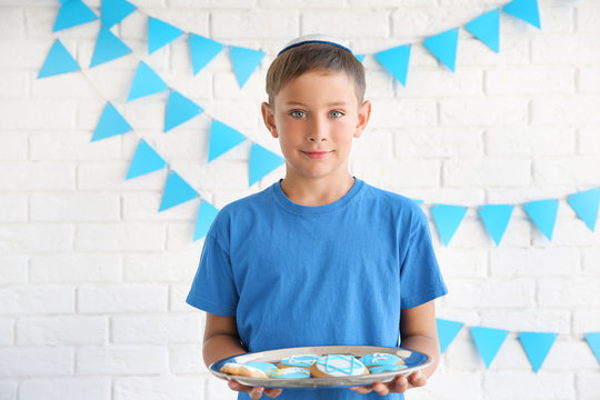 Jewish boy holding tray with festive Hanukkah cookies at home