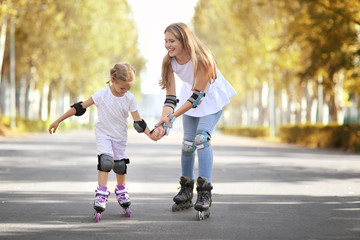 Fototapeta premium Mother with daughter rollerskating in park