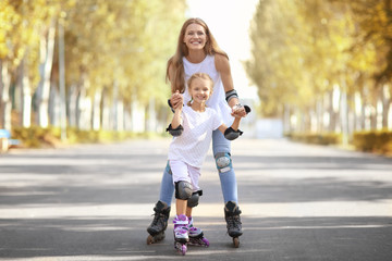 Mother with daughter rollerskating in park