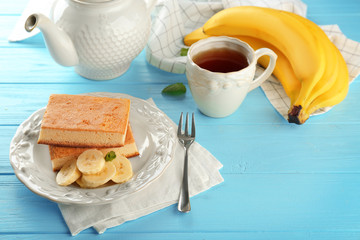 Plate with tasty banana cakes and cup of tea on wooden table