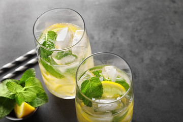 Glasses of cocktail with mint and lemon on grey background