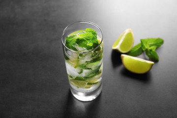 Glass of cocktail with lime and mint on grey background
