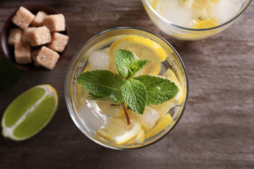 Glass of cocktail with lemon and mint on wooden table