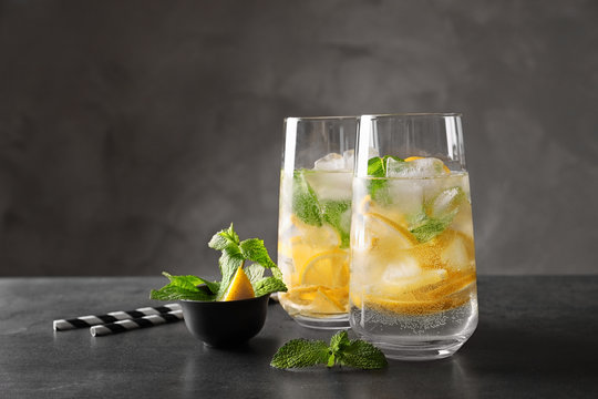 Glasses of cocktail with mint and lemon on grey background
