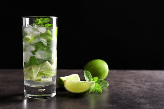 Glass of cocktail with lime and mint on table