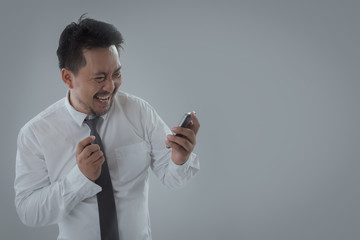 Portrait of businessman happy and holding smartphone on gray background. business, people, success, gladness and cheerful concept