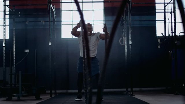  Muscular African American man strength training with ropes at the gym