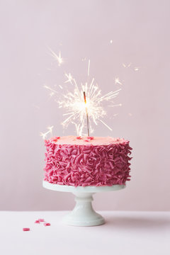 Cake with pink chocolate curls and sparkler